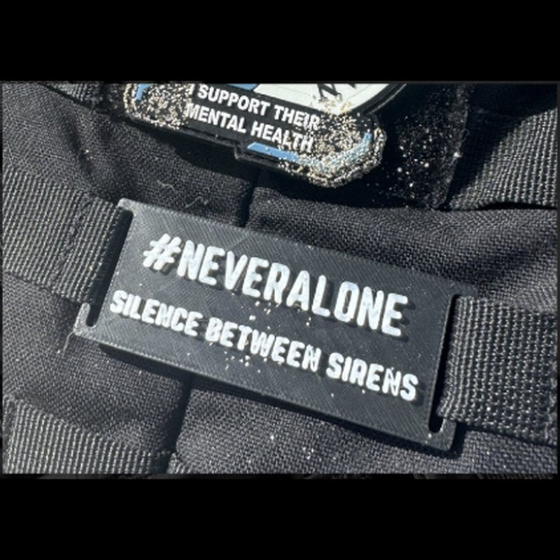 Black #NeverAlone Silence Between Sirens MOLLE tag fitted to kit